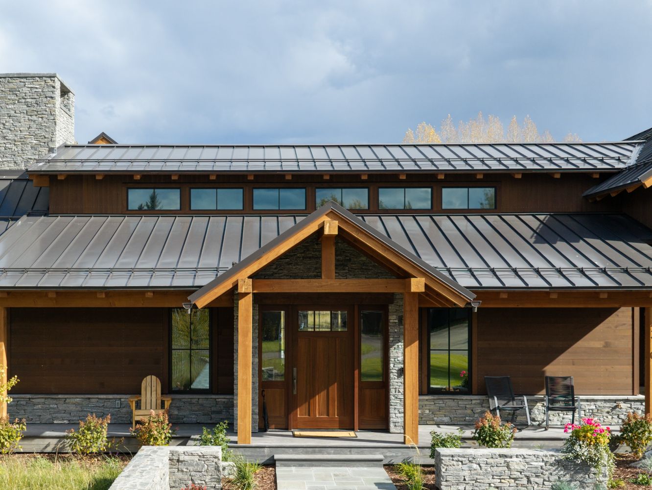 Contemporary wooden house with metal roof and landscaped garden.
